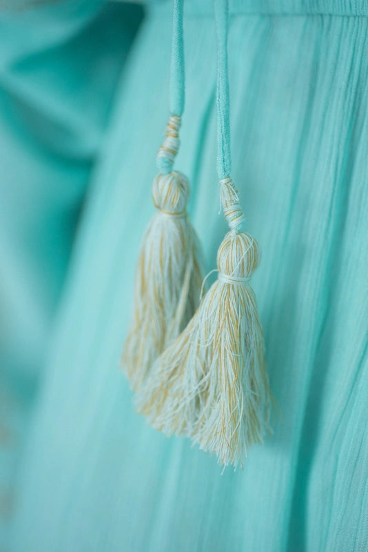 Detailansicht der Quasten am aquamarinfarbenen Boho-Kleid