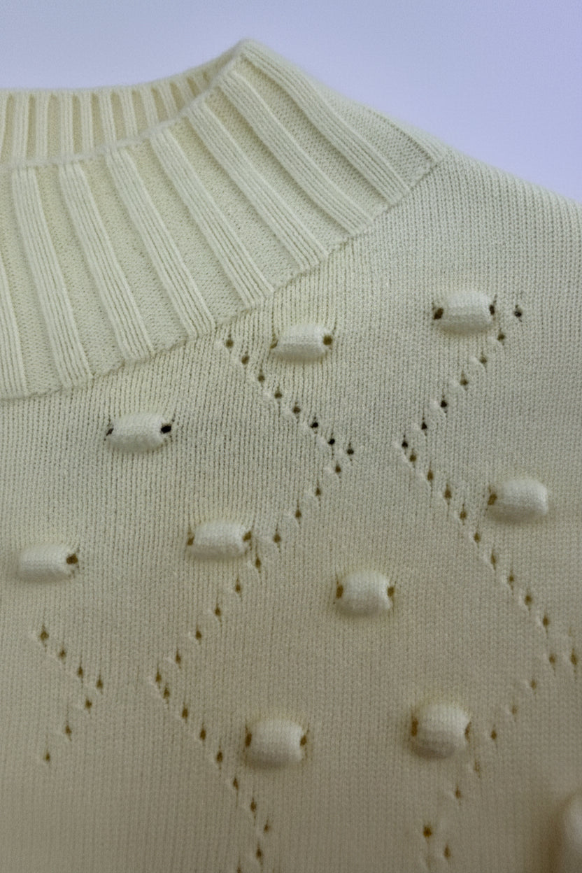 Detailansicht des Noppenmusters am gelben Pullover