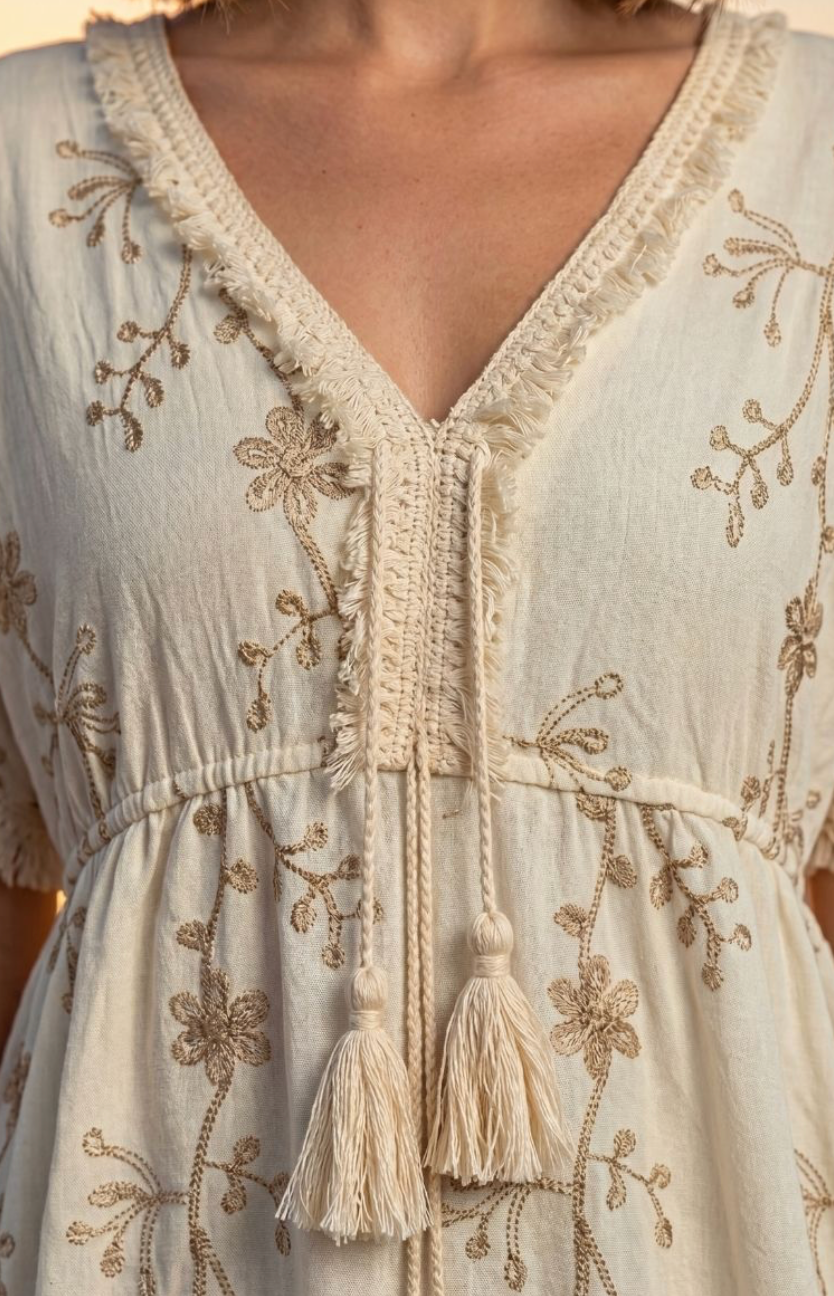 Detailansicht von Ausschnitt, Stickerei und Quasten am beigen Boho-Kleid