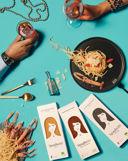 Greenomic Good Hair Day Spaghetti Sortiment – Lifestyle Flatlay mit 3 Packungen Spaghetti-Teller Garnelen und Goldbesteck auf Türkisem Hintergrund – el encanto